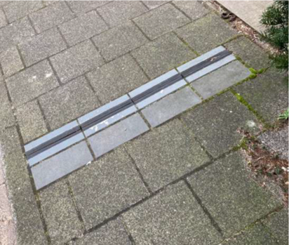 Stoeptegels met een uitsparing in de lengte waarin een kabel weggelegd kan worden.