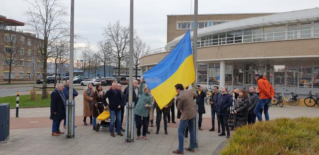 Loco-burgemeester Roland Boom hijst samen met een groep mensen de Oekraïense vlag voor het gemeentehuis