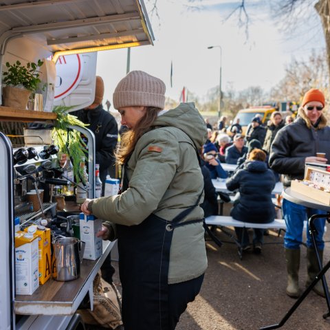 Eine Frau kocht Kaffee in einem Imbisswagen im Wald des Lebens. 