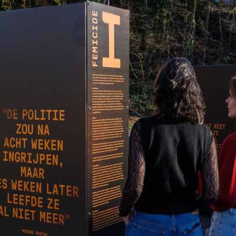 Twee vrouwen lezen de tekst bij een van de portretten