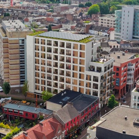 An impression of the future residential tower with solar panels on the roof. It is an aerial photo with the City Office in the background