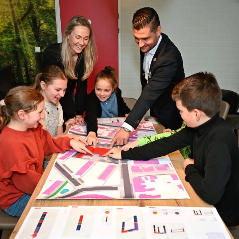 Wethouder Raoul Vinken, leerlingen van basisschool St. Ursula & hun juf wijzen naar een plattegrond van de school