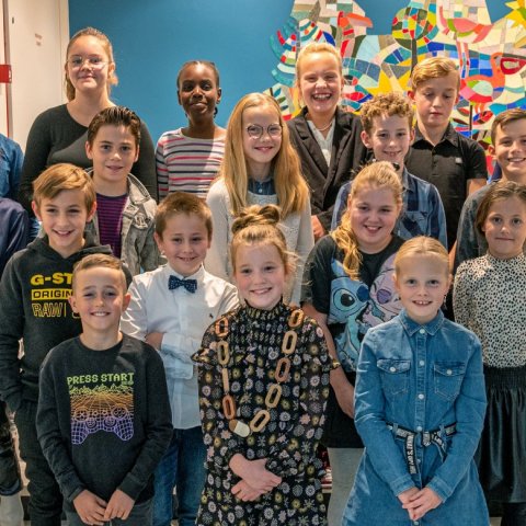 Children's Council members stand on a staircase against a colorful background and smile into the camera