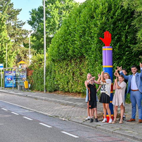 Wethouder Raoul Vinken samen met leerlingen van basisschool St. Ursula bij een gekleurde paal met handje in de buurt van de school