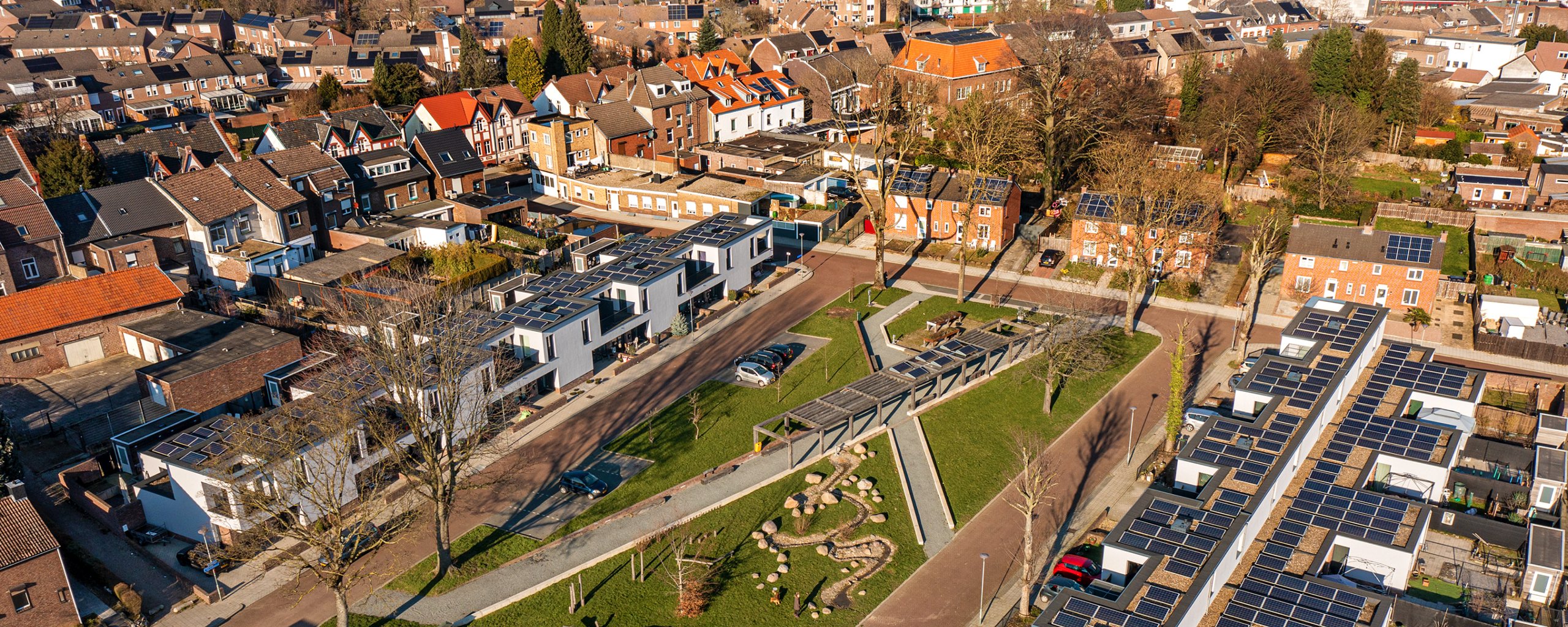 An overhead view of mayor dohmen square, a park in the middle with white new construction houses on either side with solar panels on the flat roofs.