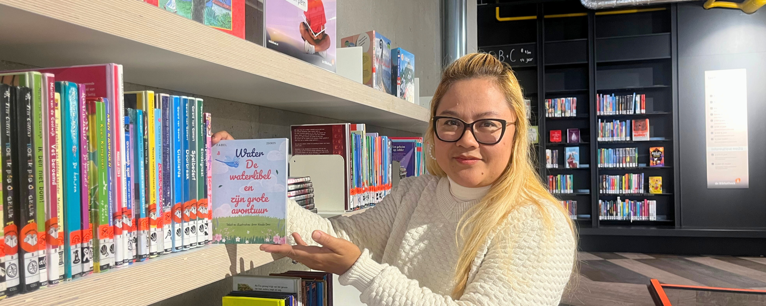 Nanda met haar eerste kinderboek in de bibliotheek