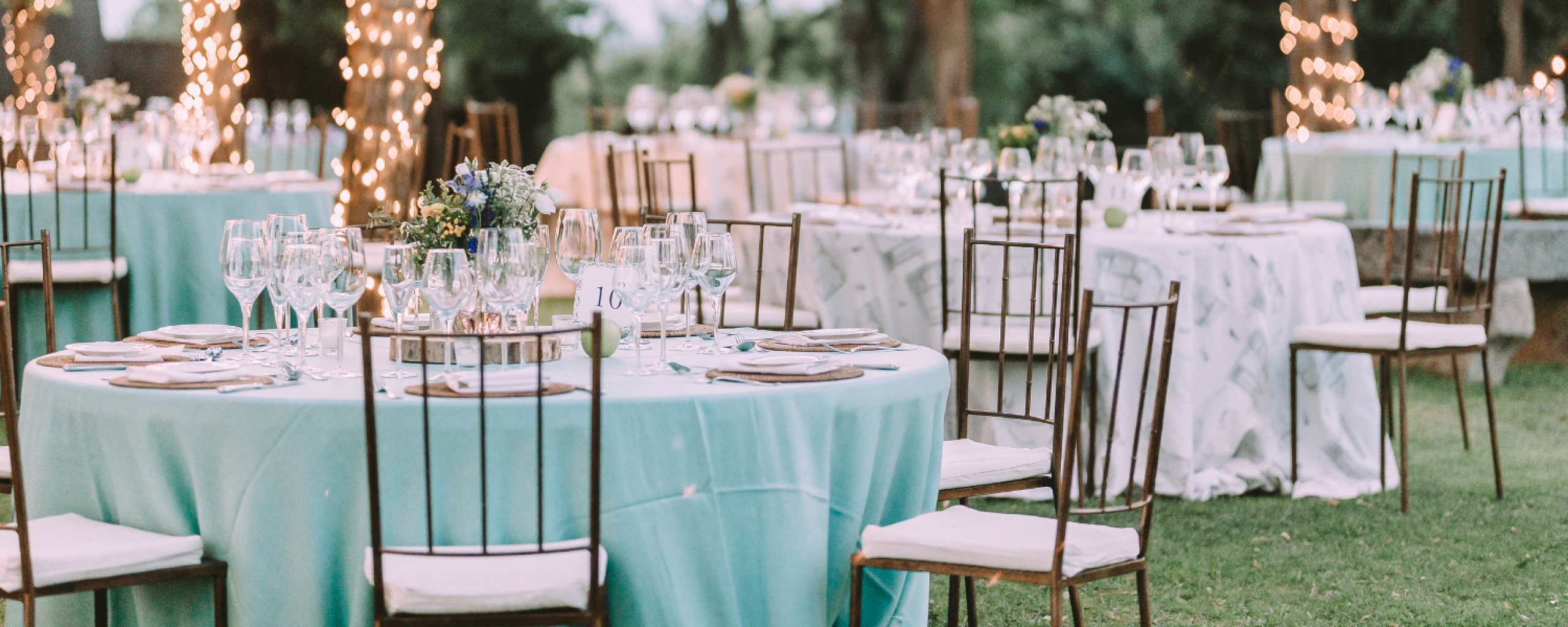 Covered tables at a wedding venue surrounded by garlands of lights