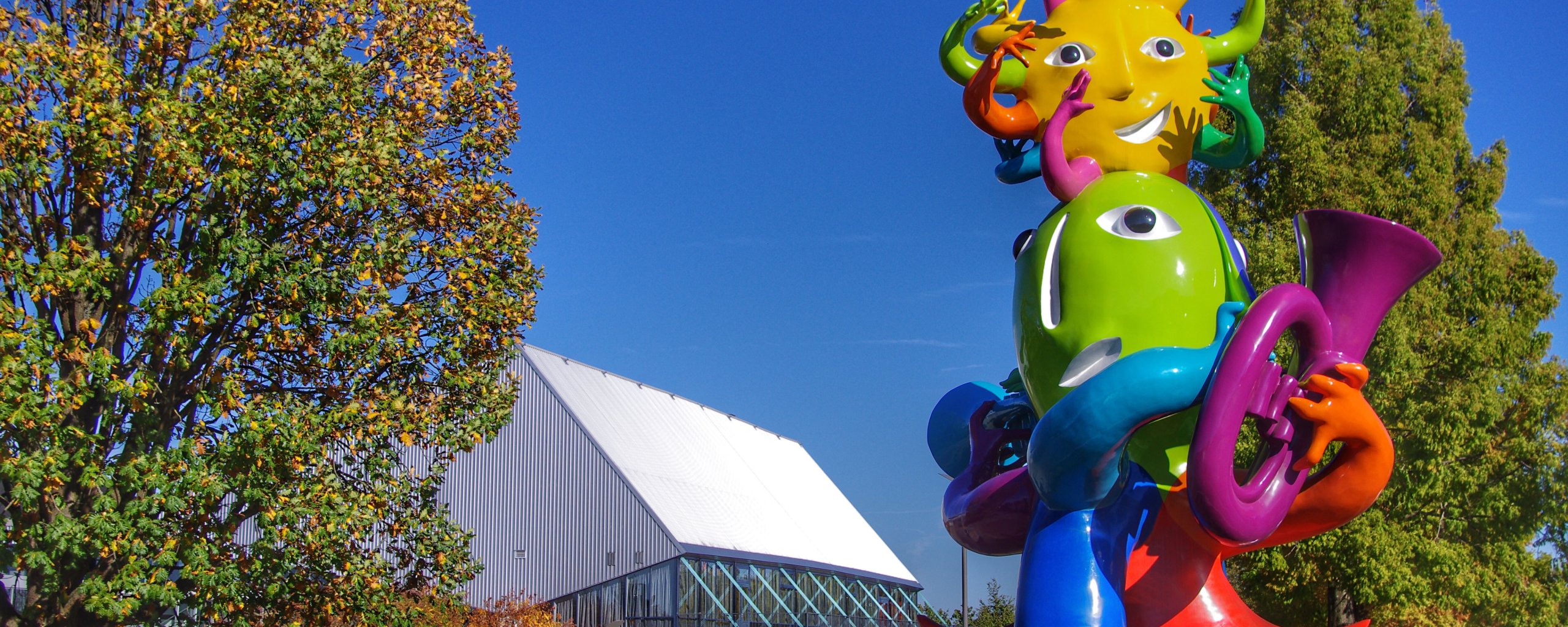 A sunny photo of the colorful statue Viva La Vida with Europaplein and the Rodahal in the left background.