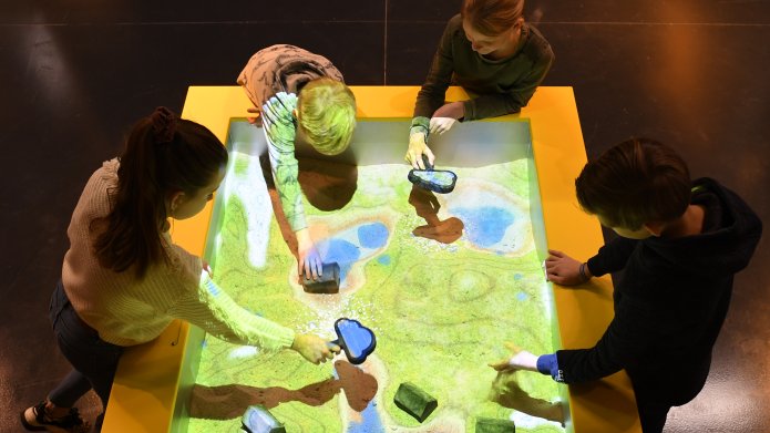 Kinderen kijken naar een gebiedsplattegrond met loepjes in de vorm van een wolk