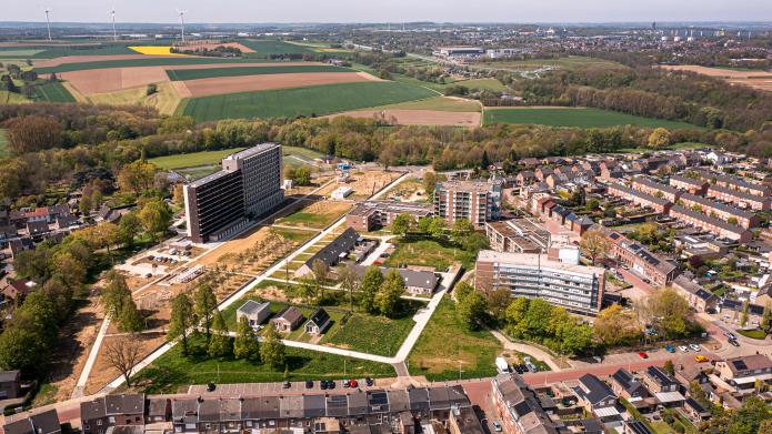 Een luchtfoto van het SUPERLOCAL gebied. Links de flat. Op de achtergrond velden en het Parkstad Limburg stadion
