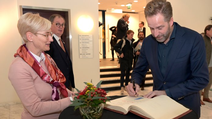 Minister Hugo de Jonge tekent het gastenboek van Kerkrade op het Raadhuis.