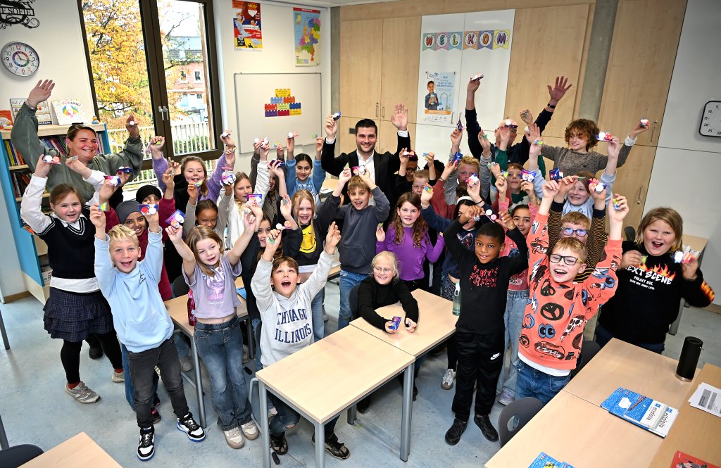 Wethouder Raoul Vinken staat tussen een groep leerlingen van IKC Droomhof in terwijl ze allemaal de lampjes in de lucht houden
