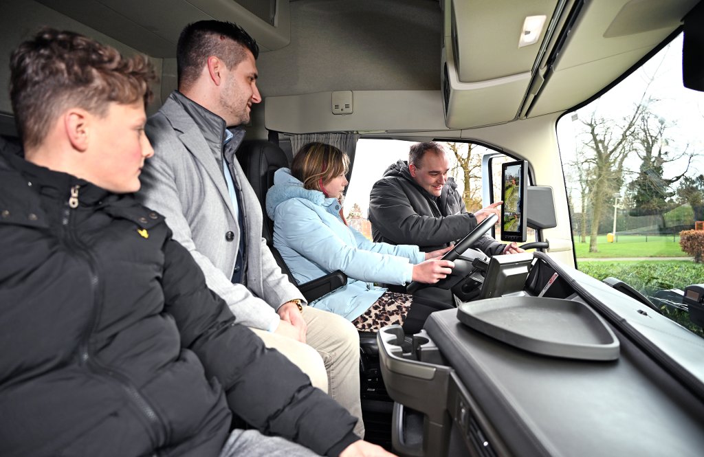 Wethouder Raoul Vinken samen in de vrachtwagen met twee leerlingen terwijl ze uitleg krijgen van een persoon die les geeft over de dode hoek