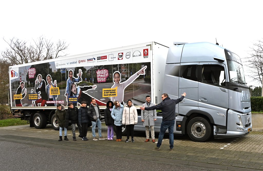 Een groepsfoto met de wethouder, de leerlingen en de persoon de de les kwam geven voor de vrachtwaren die is gebruikt tijdens de praktijkles