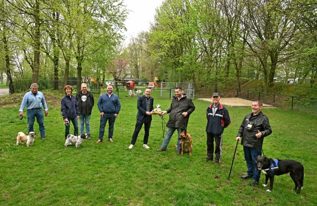 Een groep mensen met honden op een grasveld.