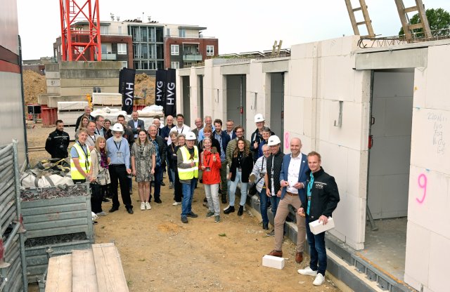 Een groep mensen staat voor huizen in aanbouw