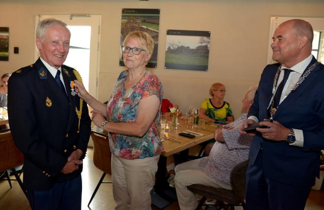 De heer Canna krijgt zijn lintje opgespeld. Locoburgemeester Jongen kijkt toe. 