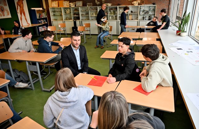 Stadtrat Raoul Vinken im Gespräch mit einigen Schülern in einem Klassenzimmer, im Hintergrund Schüler, die mit einer VR-Brille an einer Verkehrserziehung teilnehmen.
