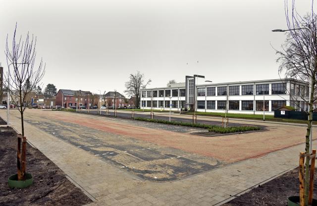 Overzichtsfoto van het nieuwe Old Hickoryplein met op de achtergrond het voormalig LTS-gebouw. De parkeervakken van zwarte stenen liggen naast elkaar. De rijweg is met rode stenen aangelegd. Rond het plein loopt een stoep. In het midden en rond het plein staan jonge bomen. 