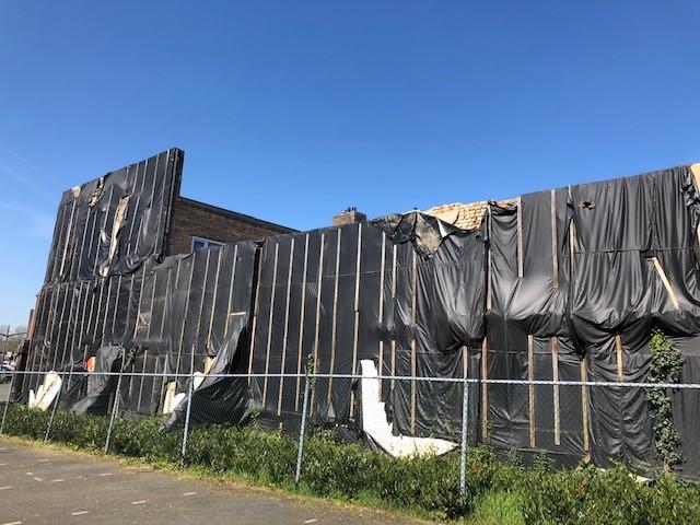 De gevel is afgedekt met zwart bouwzeil, er staat een hek om het gebouw