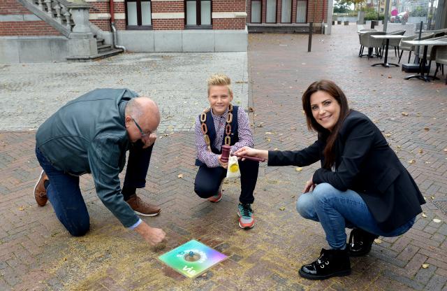 Kinderburgemeester Hidde Sieler, wethouder Jo Schlangen en initiatiefneemster Tanja Bindels nemen knikkertegel voor het Raadhuis in gebruik