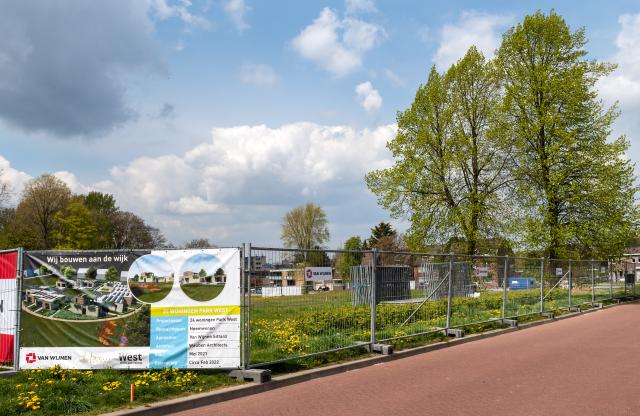 Bouwhekken met daarop zeilen met impressies van hoe het gebied met de parkwoningen eruit gaat zien. 