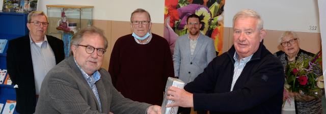 Wethouder Huub Wiermans (links) overhandigt voorzitter Henk Derix van de Cliëntenraad Werk & Inkomen Kerkrade een cadeau ter gelegenheid van de officiële opening van haar nieuwe onderkomen in het Flexiforum. Op de achtergrond enkele bestuursleden van de Cliëntenraad.