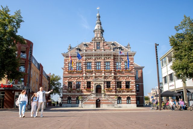 The Town Hall on a sunny day, three people walking by in the foreground