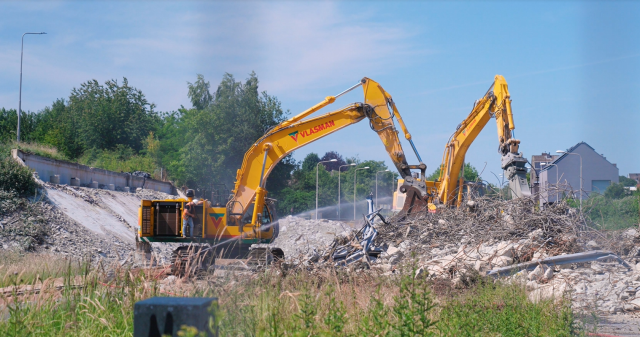 Twee gele graafmachines aan het werk in het puin van het gesloopte viaduct aan de Roderlandbaand