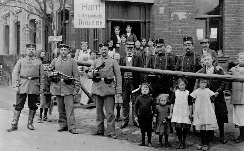 Oude groepsfoto van douaniers en inwoners bij de grenspost op de Nieuwstraat