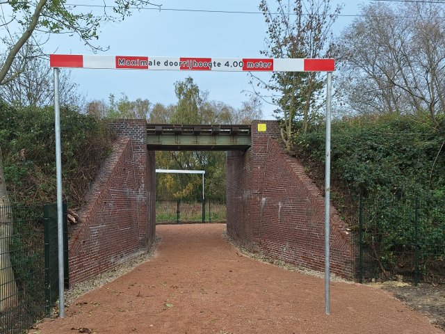 Een onderdoorgang onder het spoor. Ervoor een balk die waarschuwt voor de max. doorrijhoogte. 