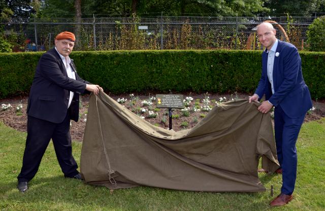 Wethouder Tim Weijers en veteraan dhr. Piet Heuts onthullen het informatiebord bij het Witte Anjerperk in het Kerkraadse Stadspark.