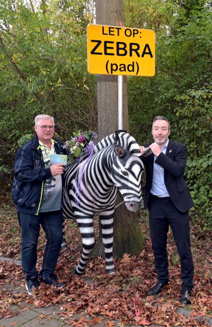 Wethouder Alexander Geers reikt prijs uit bij de levensgrote zebra aan winnaar winactie 