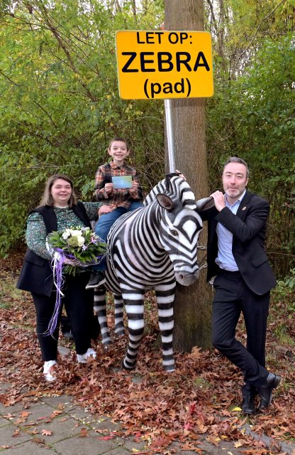 Wethouder Alexander Geers reikt prijs uit bij de levensgrote zebra aan winnaar winactie en haar zoon