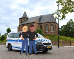 Een wit busjes met blauwe strepen met daarop het logo van gemeente Kerkrade en de tekst Handhaving. Het busje staat voor een kerk geparkeerd. 