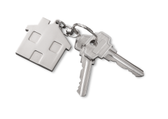 Twee huissleutels aan een sleutelring met daaraan een zilverkleurige sleutelhanger in de vorm van een huisje