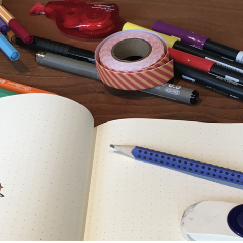 Een voorbeeld van een bullet journal. Er omheen liggen pennen en stiften. 