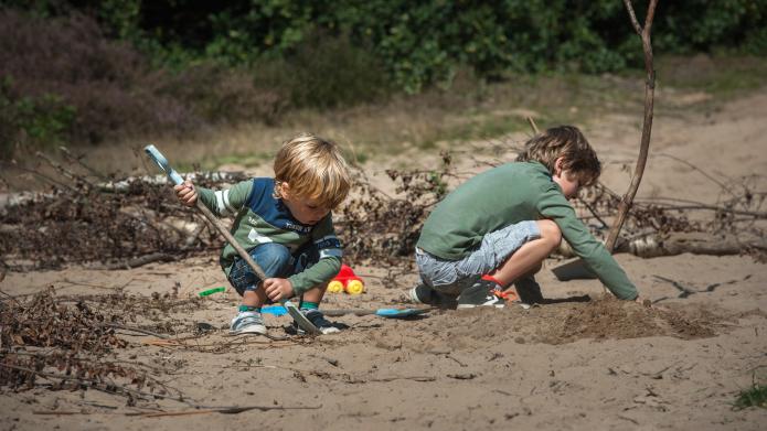 Twee kinderen die met een schep spelen in het zand van de duinen van Rozendaal.