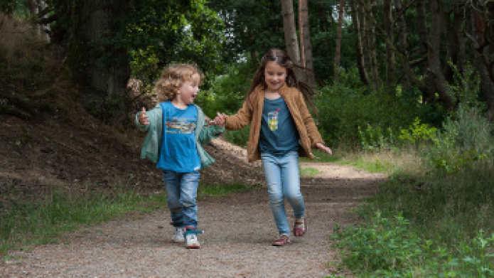 Twee kinderen rennend over een bospaadje