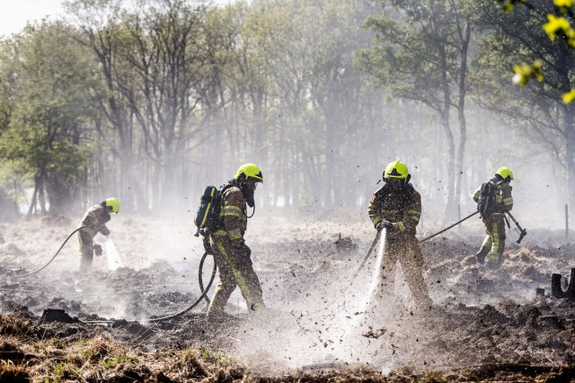 Brandweermannen blussen de brand op de Meinweg. 