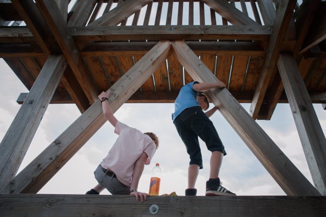 We zien twee jongens van de achterkant gefotografeerd. Ze klimmen op de uitkijktoren die uitkijkt op de Meinweg.