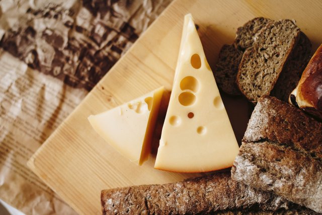 Bovenaanzicht van een kaasplank met stukjes kaas en donker brood.