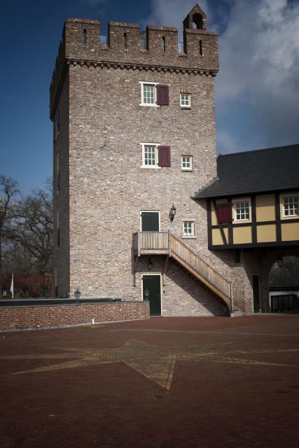 We zien de toren van Kasteel Daelenbroeck met voor op de grond een groten windroos van steen. De windoos is aangelegd in de grond.