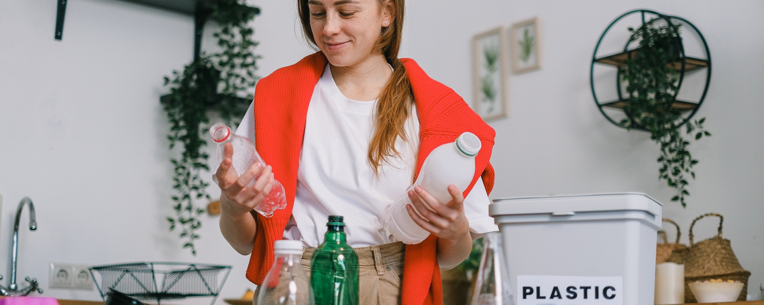 Vrouw in de keuken met plastic flessen en afvalbak