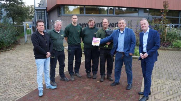 Wethouder Joop Wikkerink overhandigt medewerkers van de gemeentewerf in Aalten het bordje 'Unieke Achterhoekers aan het werk'