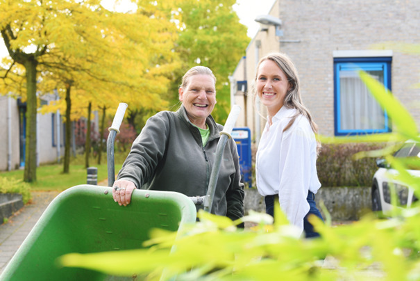 Foto van 2 medewerkers van Laborijn buiten met bomen, een gebouw en een kruiwagen