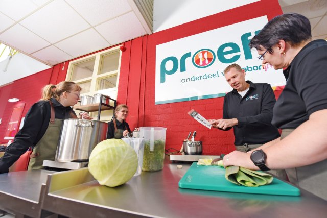 4 mensen staan in een restaurant eten voor te bereiden
