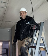 Een man in een gebouw op een ladder met een bouwhelm op