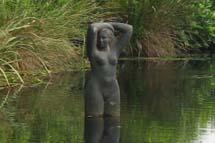 Bronzen torso van een vrouw die in het water staat