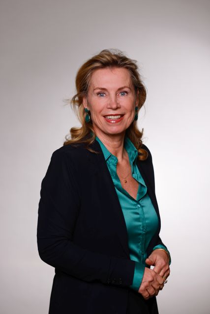 Persoon met een donker jasje en glimmende groene blouse